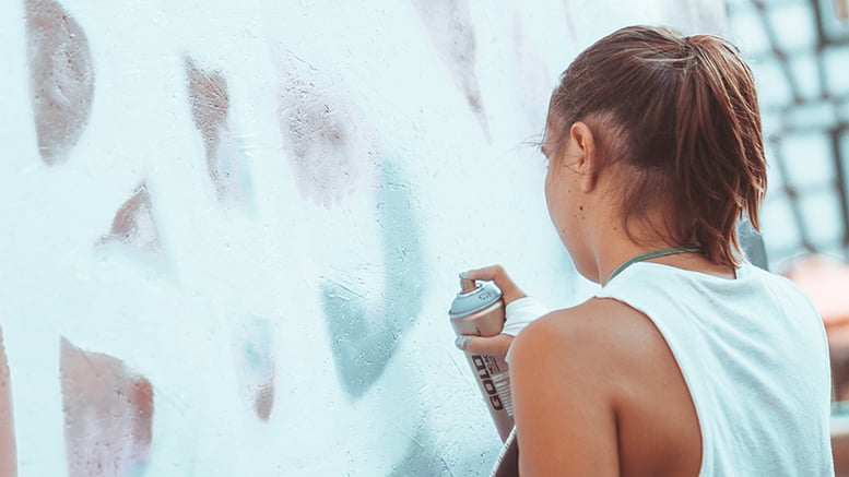 Stock photo of a young woman graffitying a wall