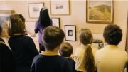 a group of school children look at art displayed in the Art Explora mobile museum.