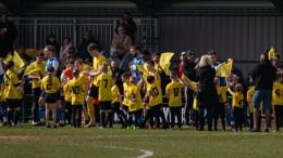 Hucknall Town players enter the pitch surrounded by young mascots
