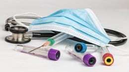 A stock photo of medical equipment, including asurgical mask, stethoscope, hyperdermic needle and blood sample tubes