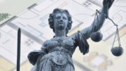 Stock image showing Lady Justice and a background of a property plan