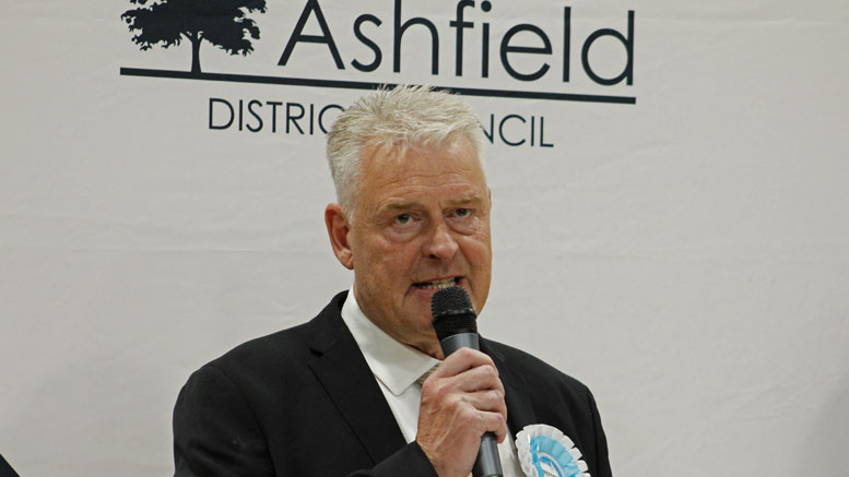 Lee Anderson n in front an Ashfield District Council banner holding a microphone as he delivers a speech